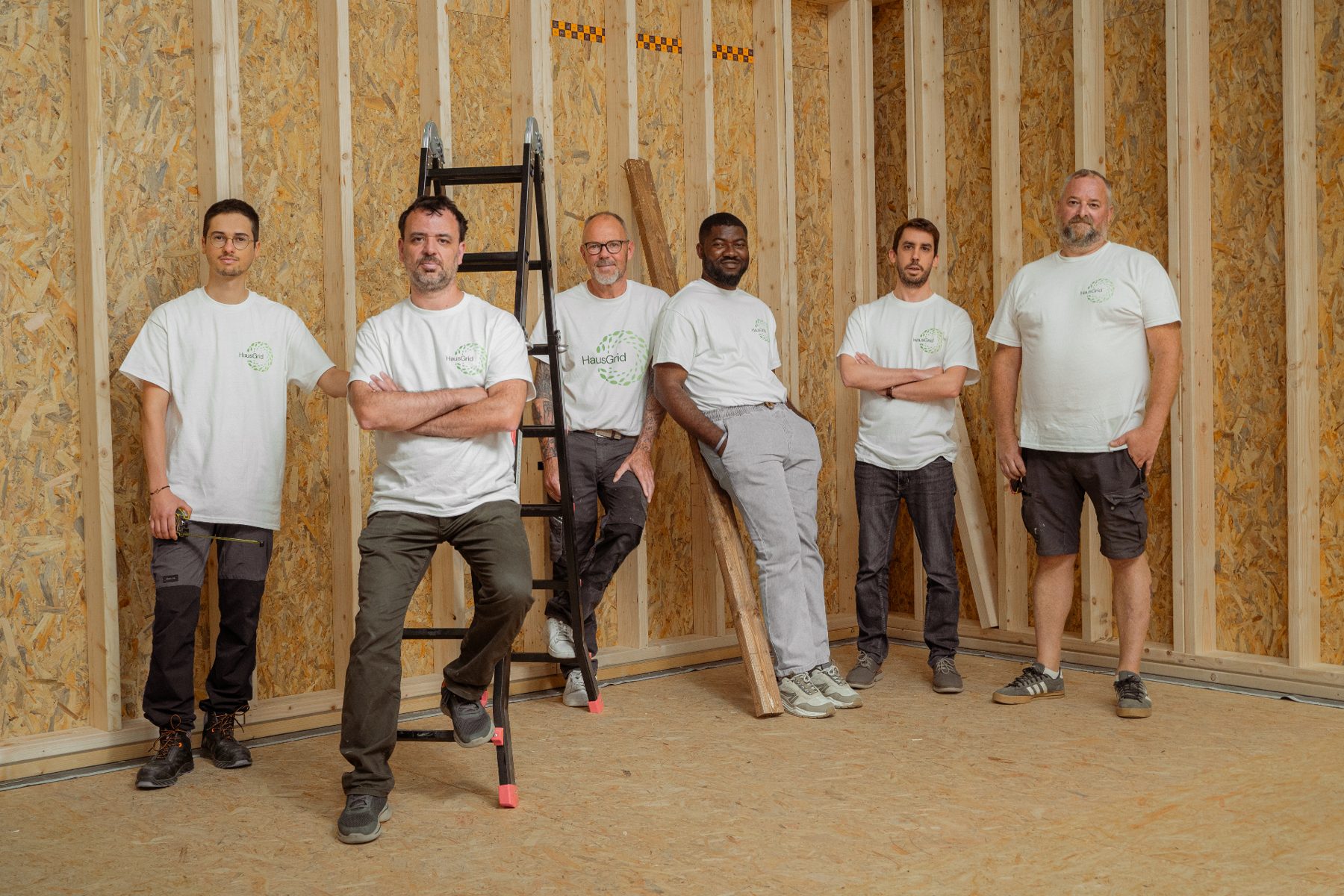 HausGrid team gathered around an assembly table in the Portuguese workshop with timber frame structure